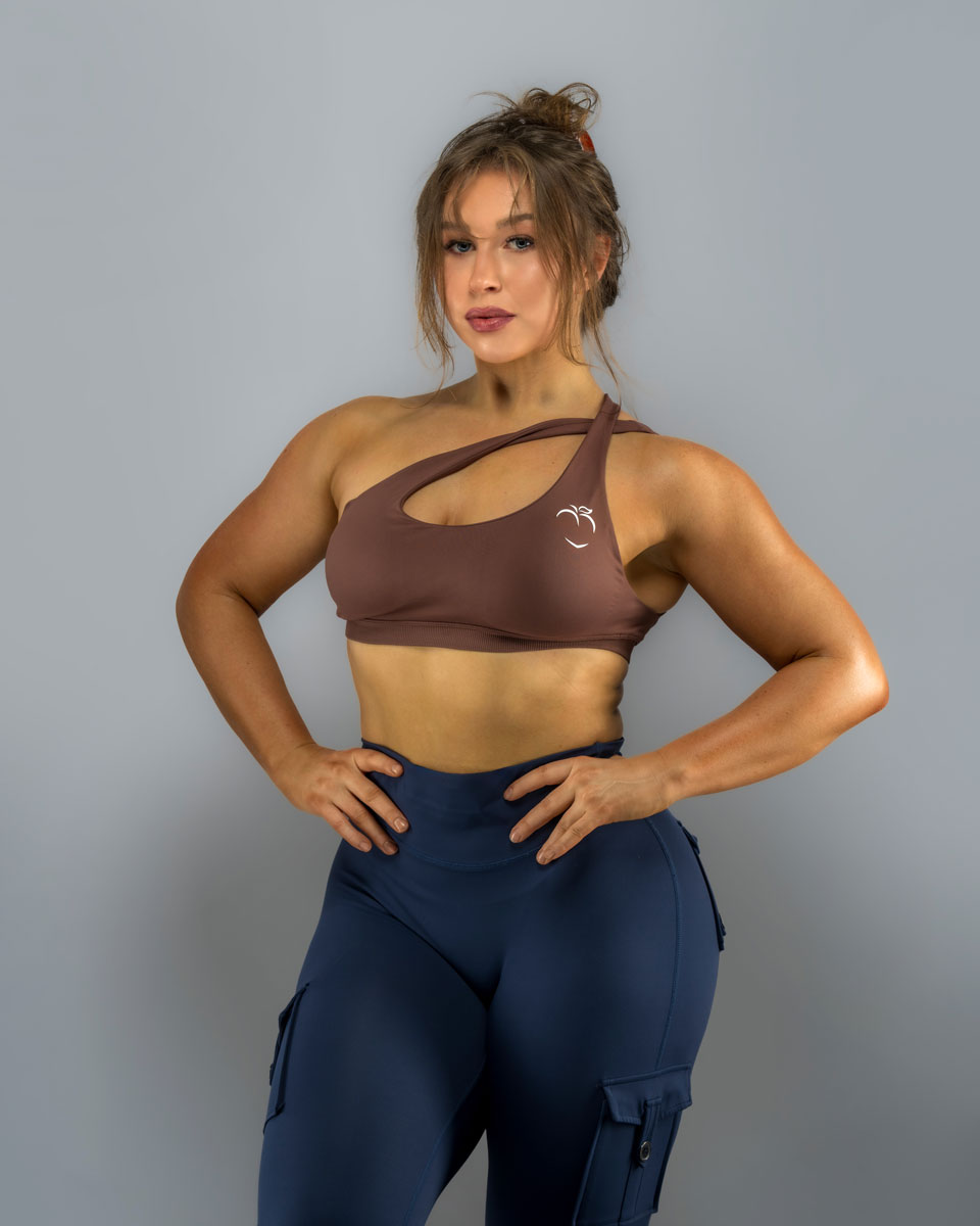 Coach is standing posing in a brown workout outfit.